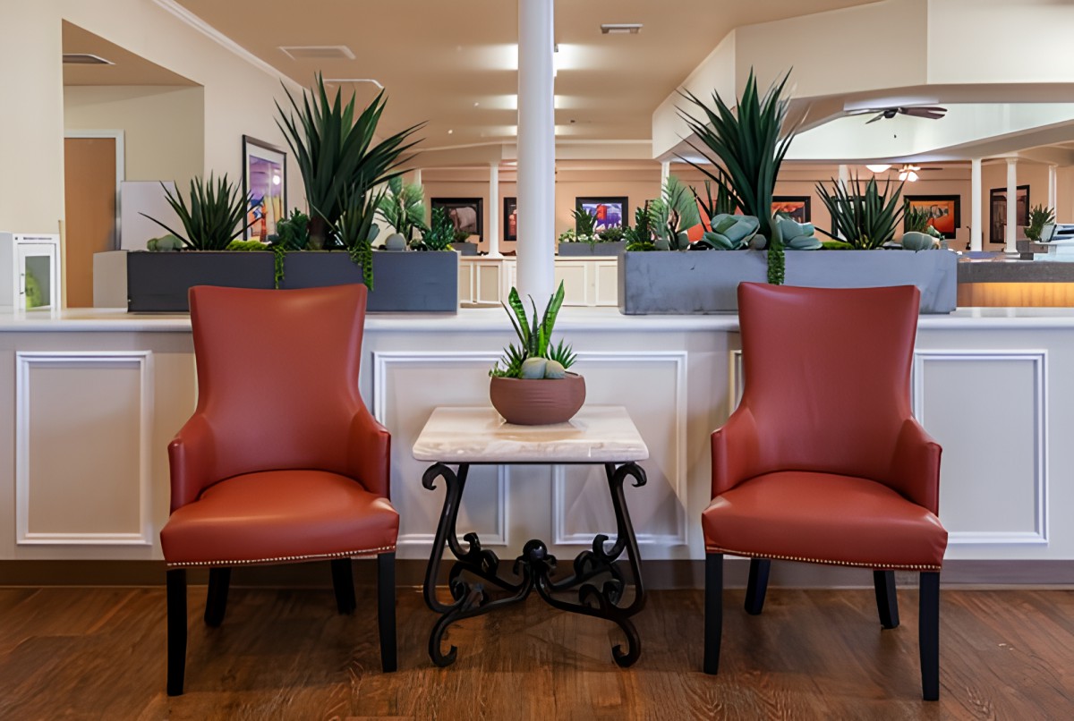 A well-decorated seating area with two red chairs and plants.