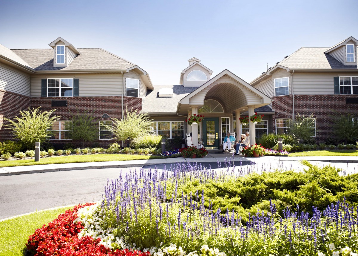 A beautifully landscaped entrance to a residential building with vibrant flowers and greenery.