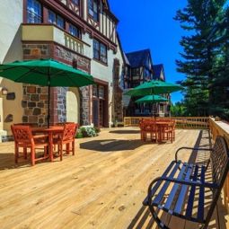 A spacious outdoor deck with tables and umbrellas, adjacent to a picturesque building.