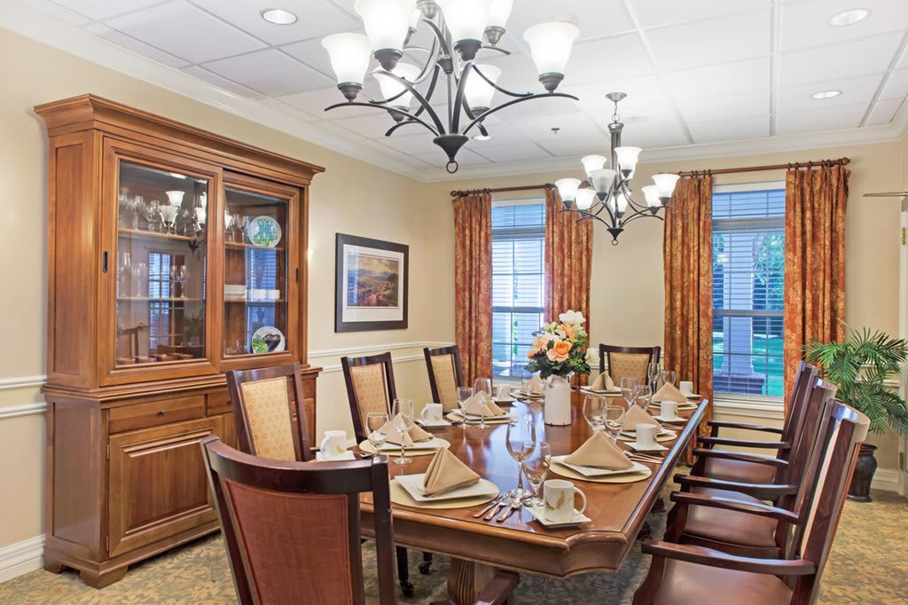 An elegantly set dining room with a wooden table, ornate chairs, and stylish chandeliers.