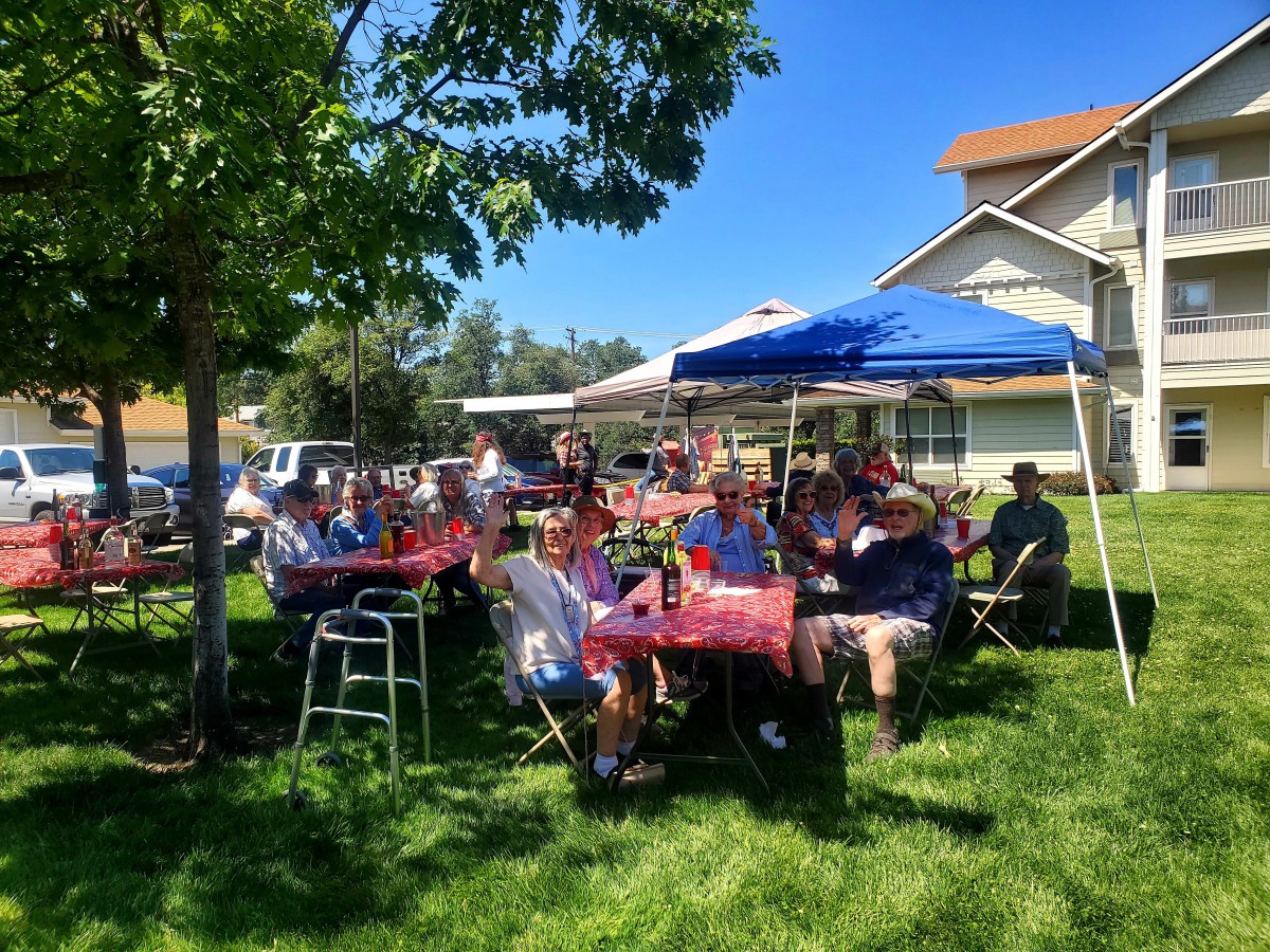 A group of people enjoying a sunny outdoor gathering under a canopy.