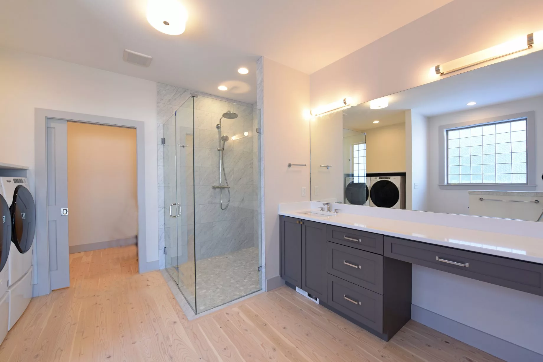 A modern bathroom featuring a glass-enclosed shower and a sleek vanity with a large mirror.