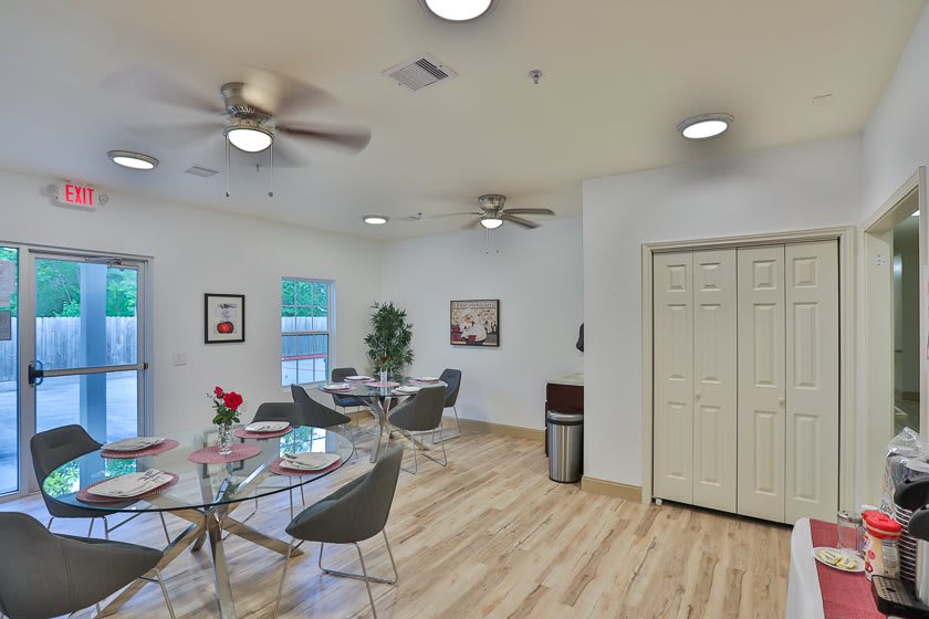 A modern dining area with stylish tables and chairs, featuring ceiling fans and ample natural light.