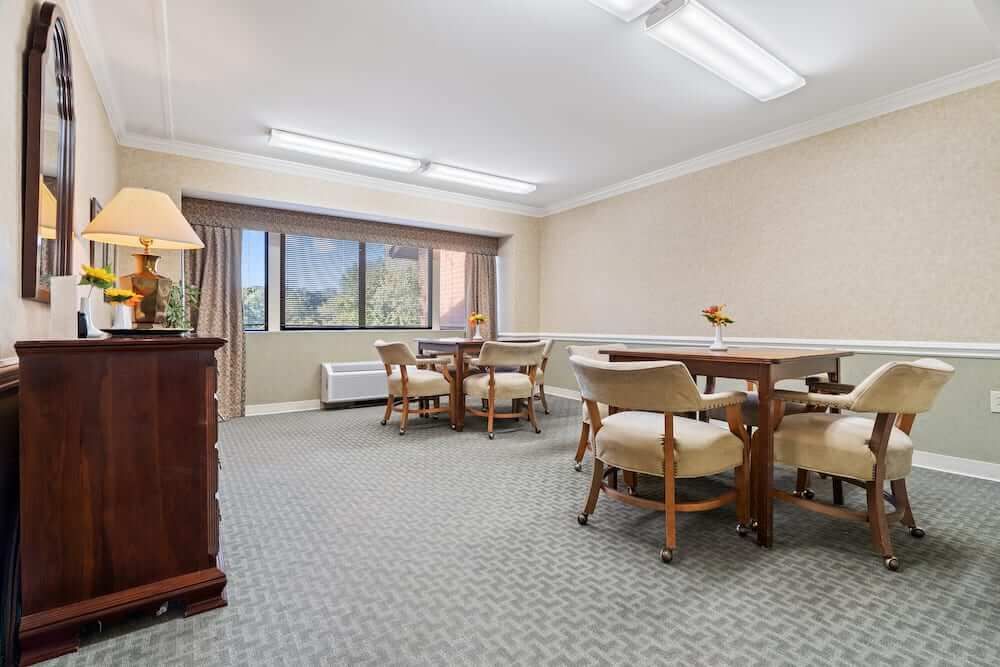 A well-lit meeting room with tables and chairs, featuring a large window view.
