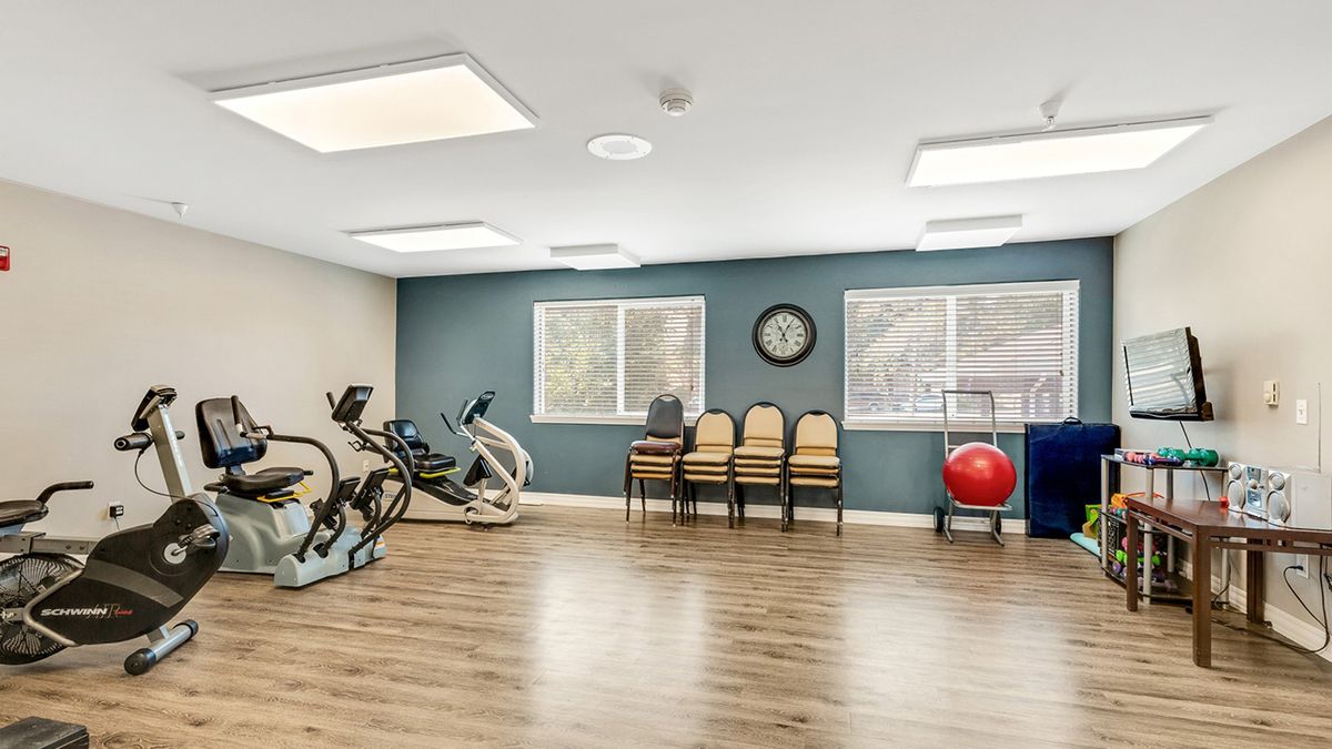 A small exercise room with stationary bikes, chairs, and an exercise ball.