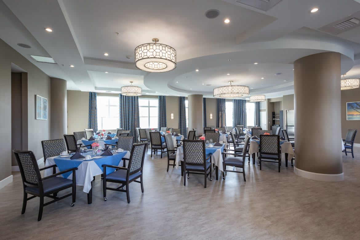A spacious dining room with elegantly set tables and modern chandeliers.