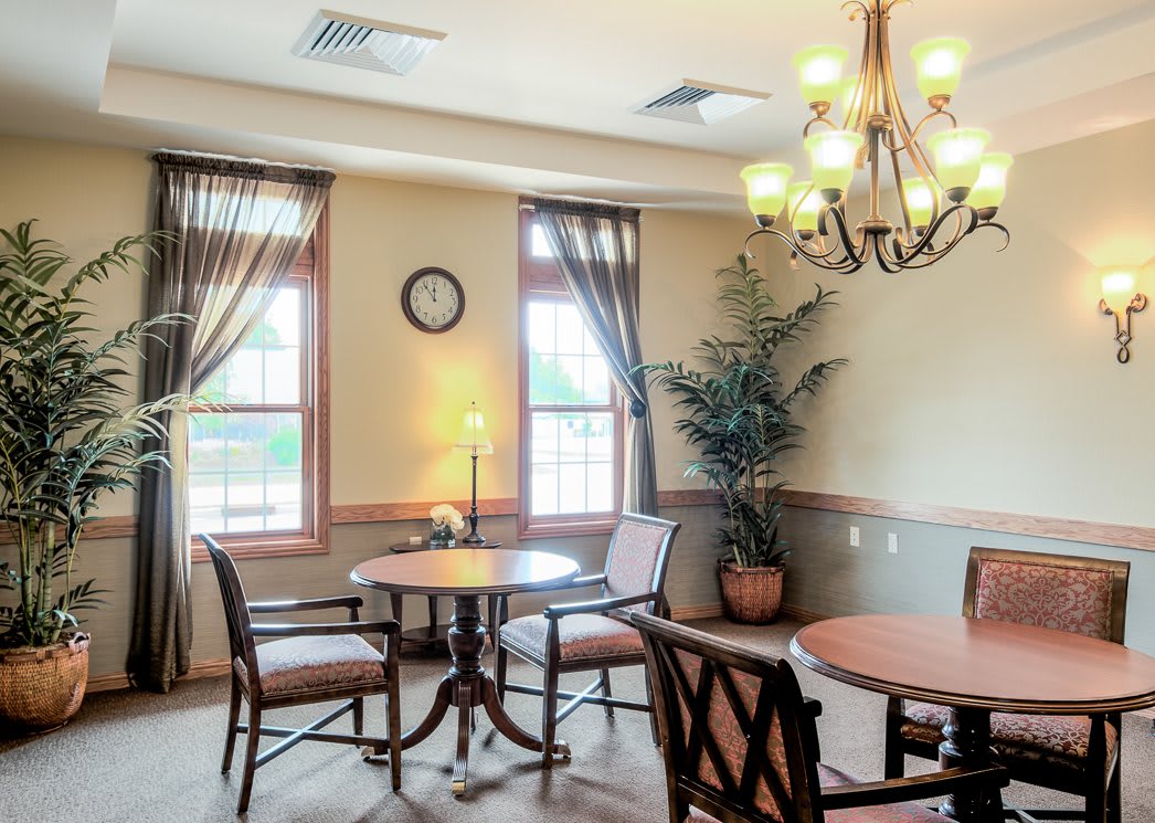 A cozy dining room with tables, chairs, and a chandelier.