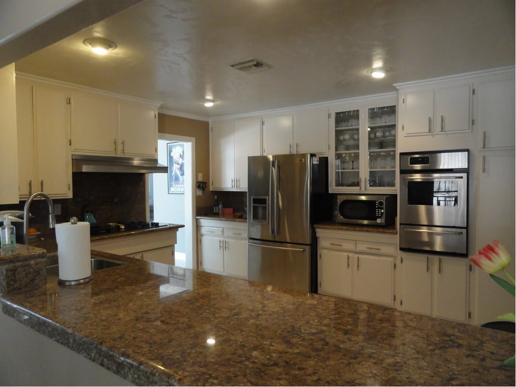 Modern kitchen with stainless steel appliances and marble countertops.