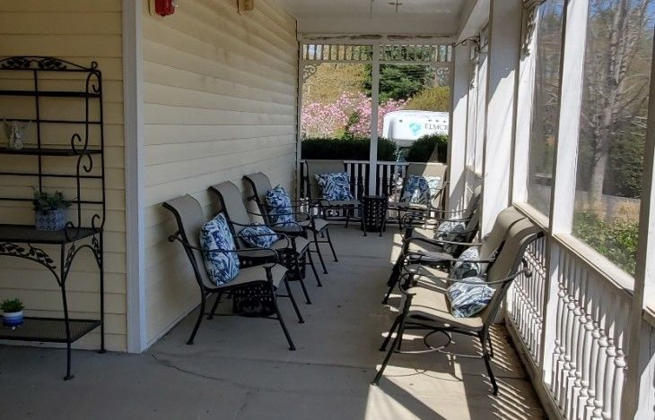 A cozy porch with several chairs adorned with floral pillows, perfect for relaxation.