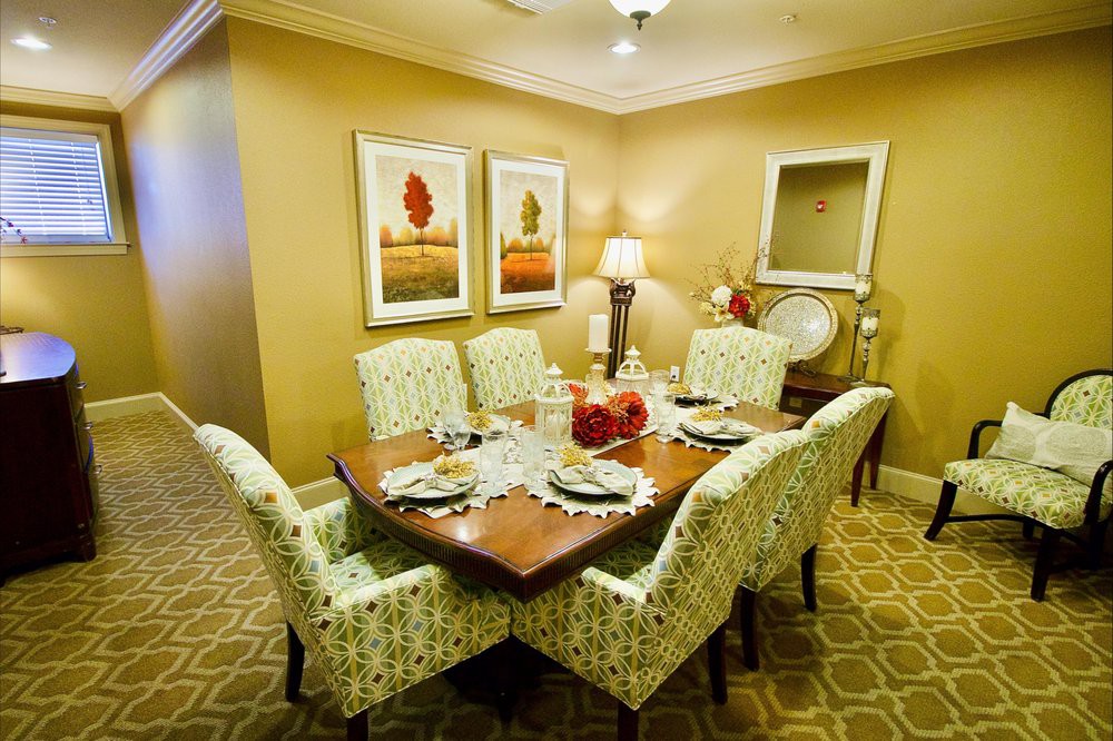 A warmly decorated dining room with a wooden table and patterned chairs, complemented by artwork on the walls.