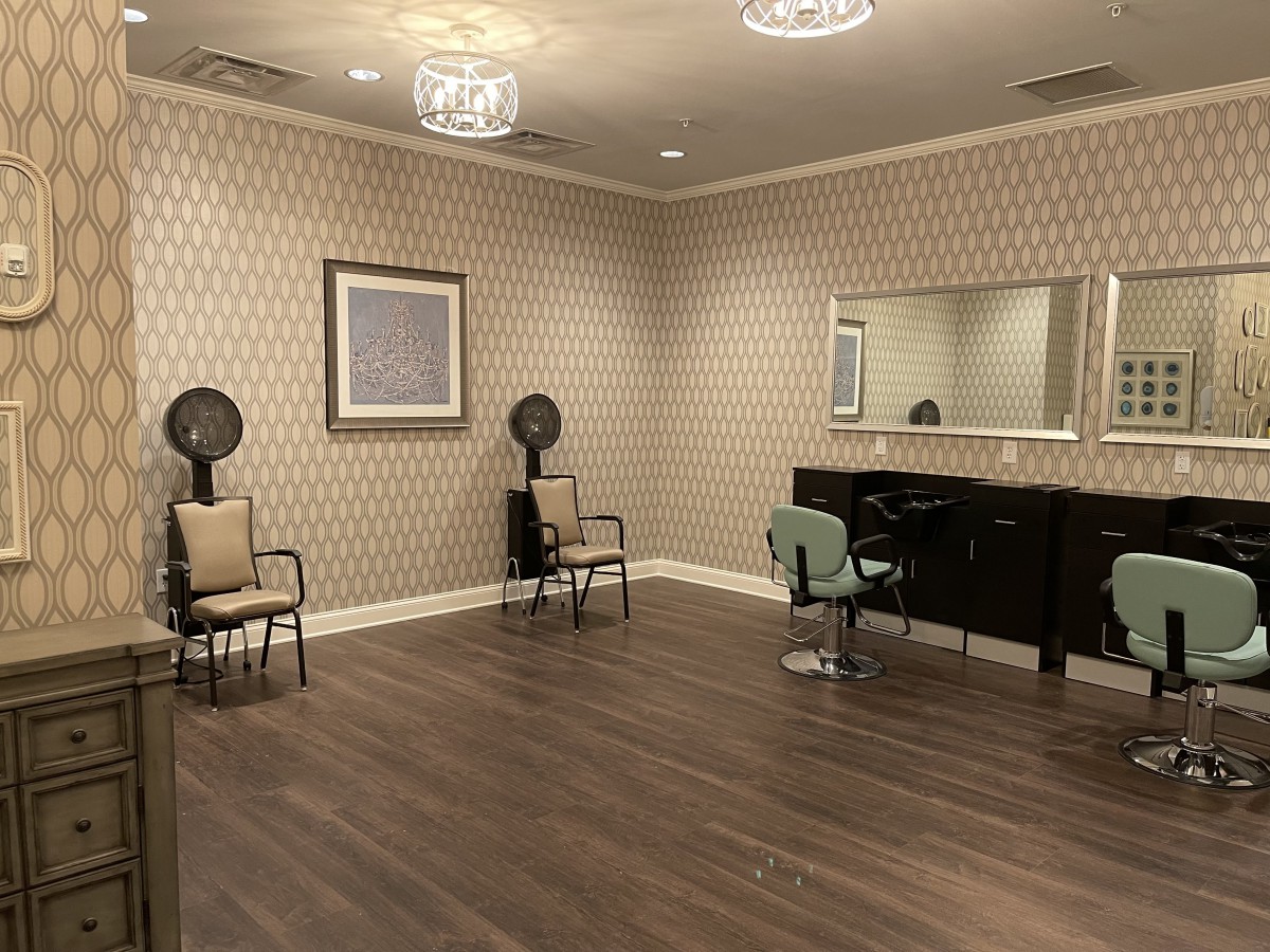 An elegant salon interior with chairs, mirrors, and hair drying stations.