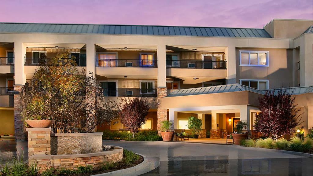 Modern hotel exterior at dusk with well-lit entrance and landscaping.
