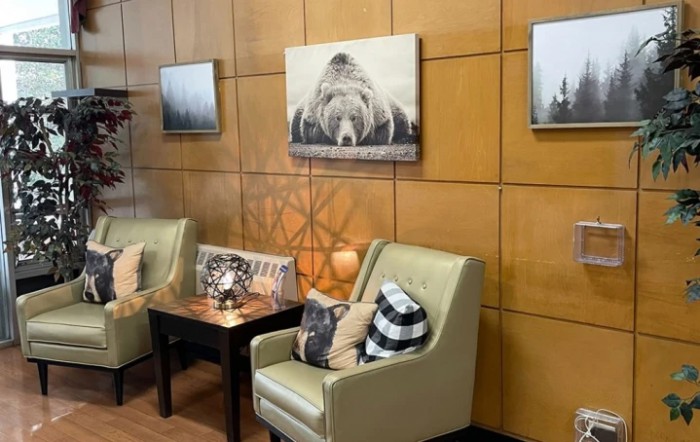 Cozy waiting area with comfortable chairs and nature-themed artwork on wood-paneled walls.
