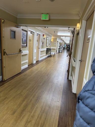 A well-lit hallway with wooden flooring and art on the walls.
