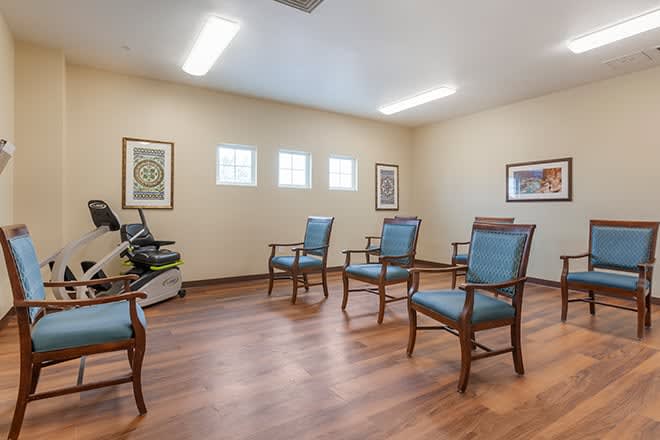 A well-lit room with wooden flooring and several chairs arranged neatly.