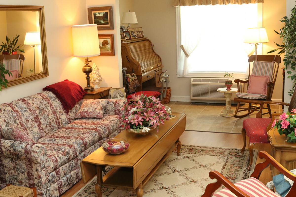A cozy living room with a patterned sofa, wooden coffee table, and warm lighting.