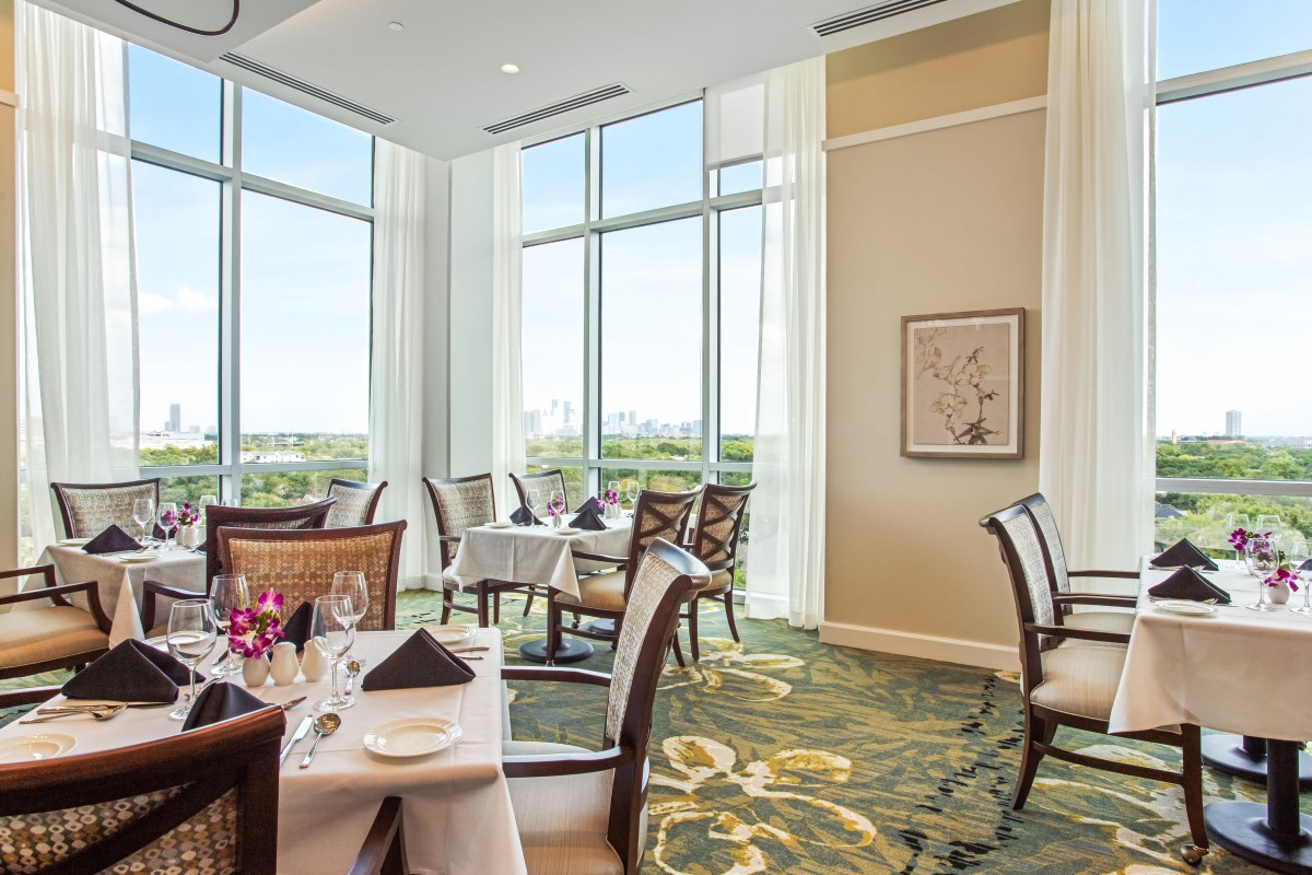 An elegant dining room in a restaurant with large windows and neatly arranged tables.