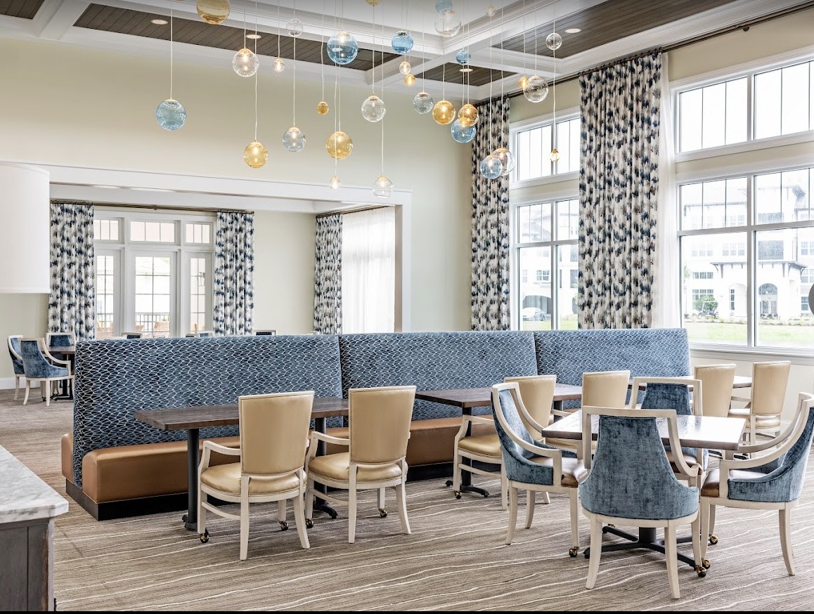 A modern dining area with elegant decor, featuring a mix of seating styles and large windows.