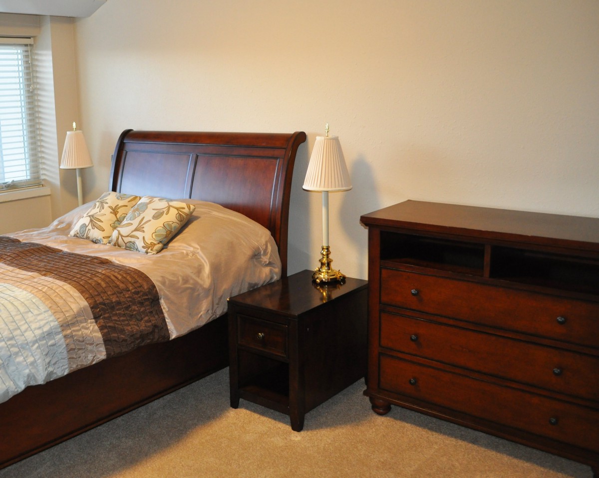 A cozy bedroom with a wooden bed, nightstand, and dresser.