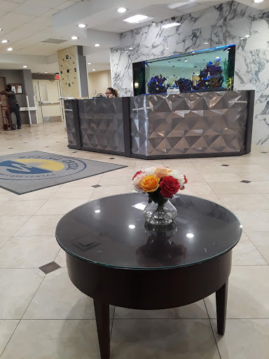 A view of a hotel lobby featuring a reception desk and a decorative table with flowers.