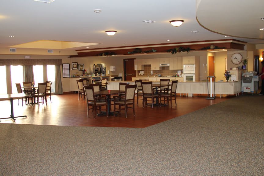 A spacious interior dining area with tables and chairs, adjoining a kitchenette.