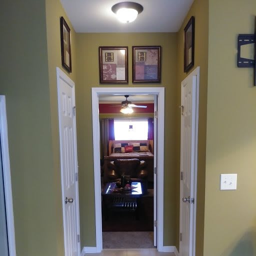 A small hallway with framed art and light fixture leading to a room.