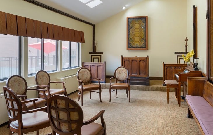 A sunlit meeting room with wooden chairs arranged in a circle.