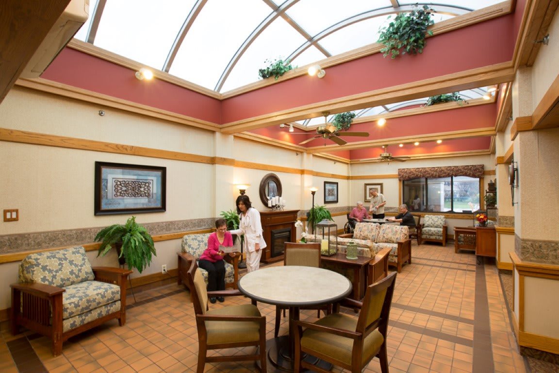 A spacious indoor lobby with seating areas, featuring tables, chairs, and decorative plants.
