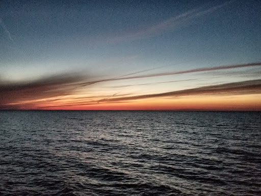 A serene sunset over the calm ocean waters, painting the sky with vibrant hues.