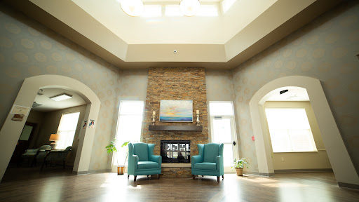 A cozy and inviting living room featuring teal armchairs, a stone fireplace, and ample natural light.