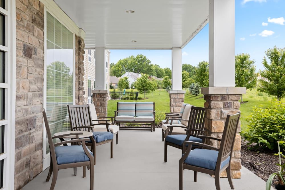 A cozy covered porch with cushioned chairs and a view of the garden.