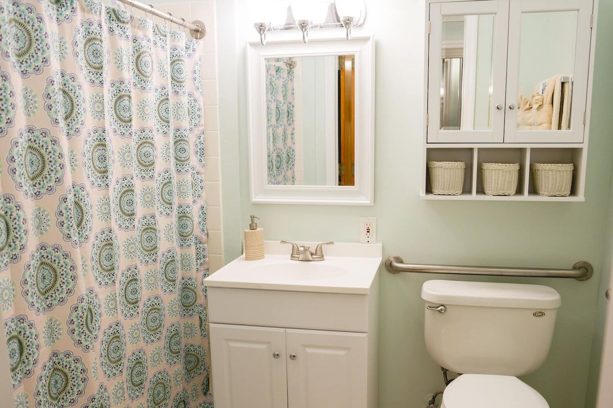 A well-organized bathroom with a sink, mirror, toilet, and shower curtain.