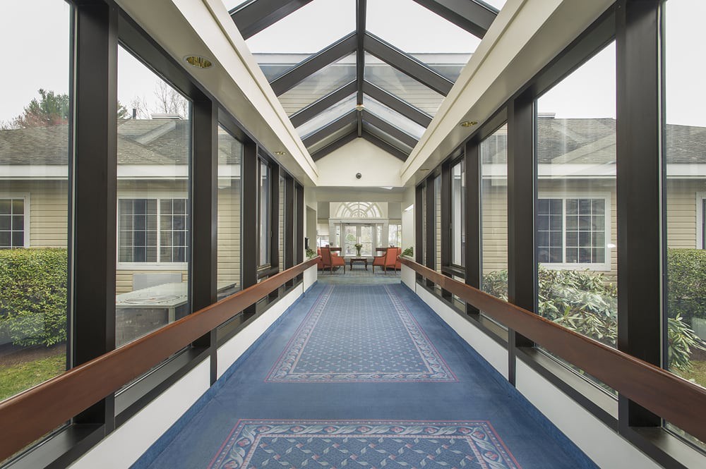 A modern hallway with a glass roof and large windows on both sides.