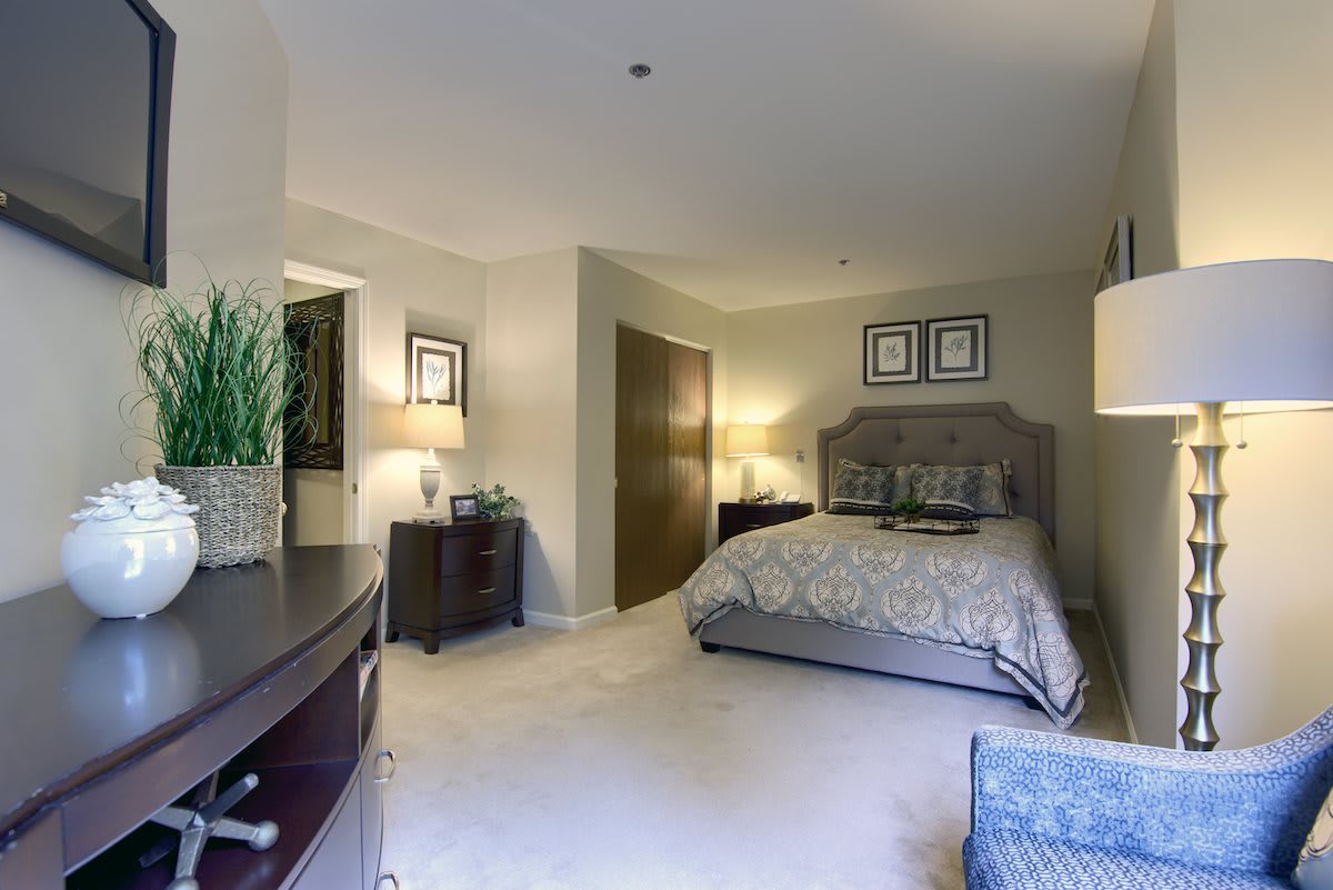A modern bedroom with a neatly made bed, stylish decor, and ambient lighting.