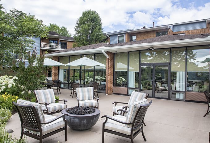 A cozy outdoor patio area with cushioned seating and a fire pit, located outside a residential building.