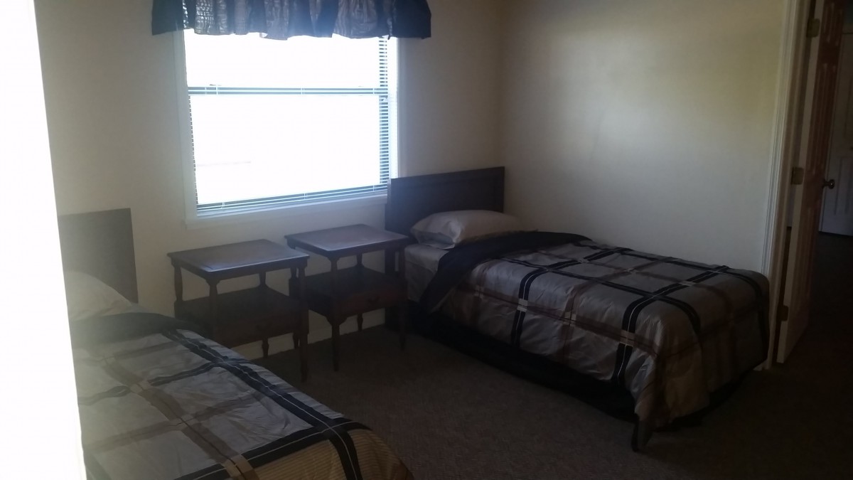 A simple bedroom with two single beds and a window.