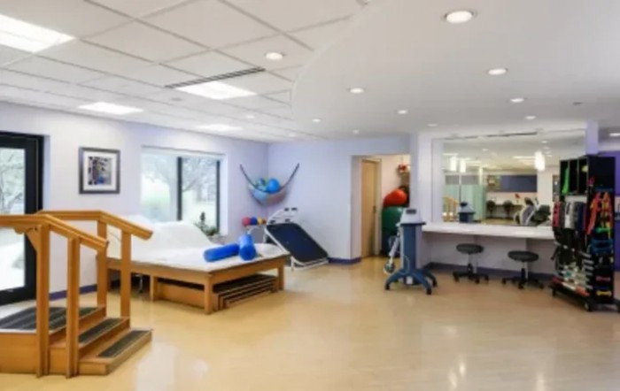 A spacious rehabilitation center room equipped with various physical therapy tools and exercise equipment.