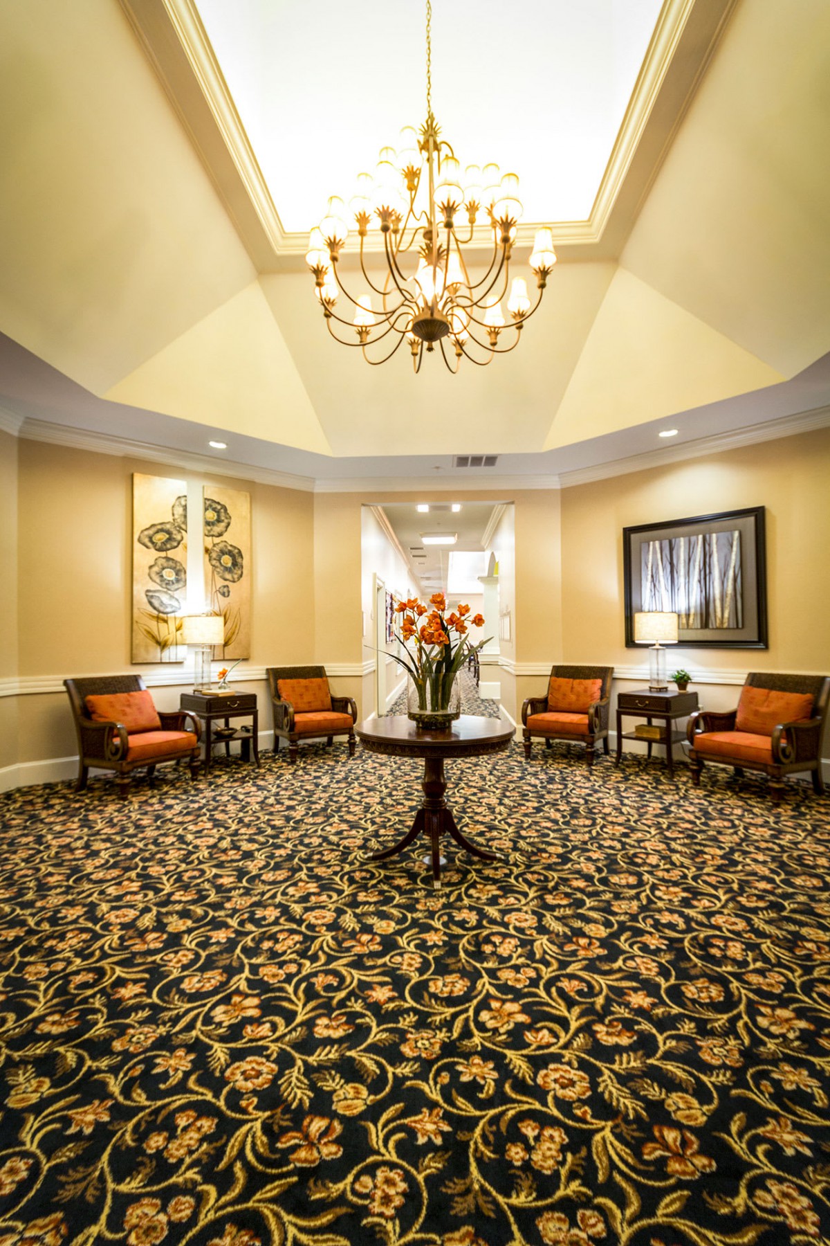 Elegant lobby with a chandelier, comfortable seating, and floral centerpiece.