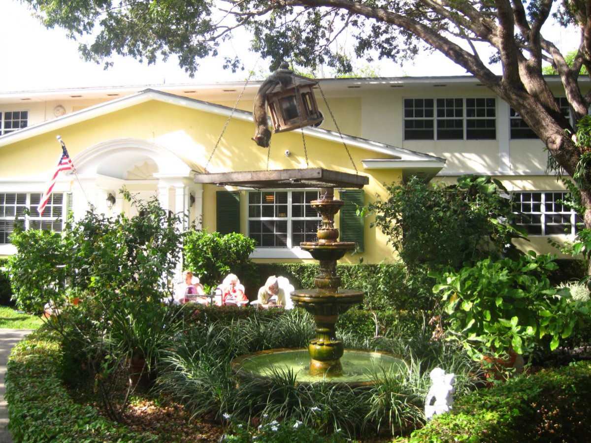 A charming house with a lush garden featuring a fountain and vibrant flowers.