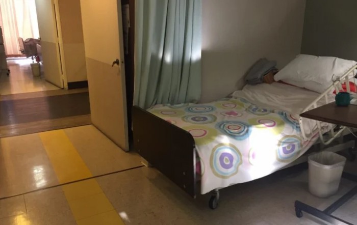 A hospital room with a single bed and privacy curtain.