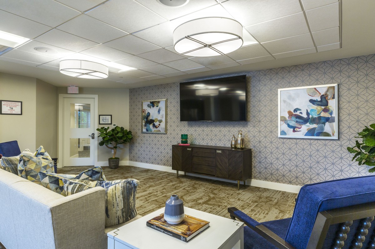 A modern living room with stylish decor, featuring a large television and contemporary artwork.