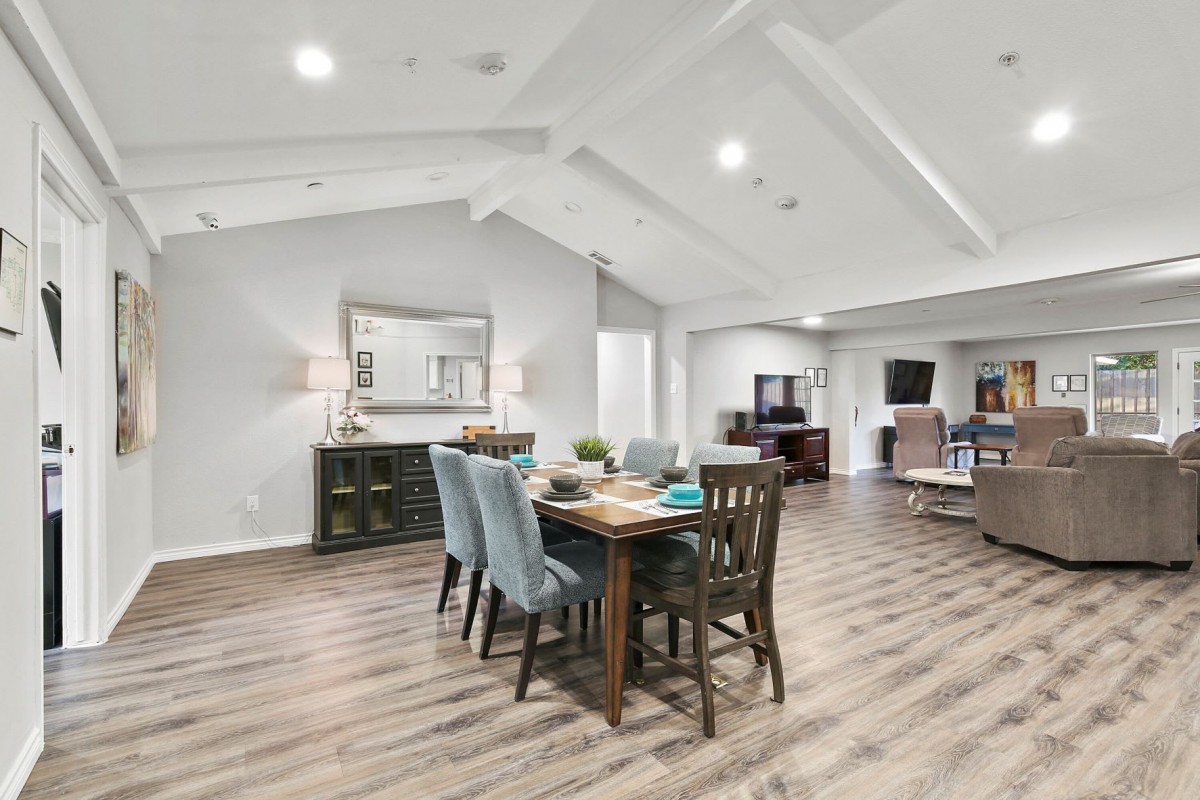 A spacious and modern open-concept living area with a dining table, vaulted ceiling, and wood flooring.