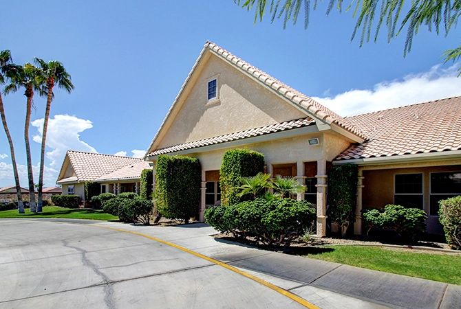A sunny day view of a building with a driveway and well-maintained landscaping.