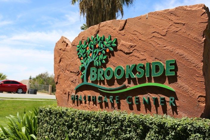 Entrance sign to Brookside Wildlife Center surrounded by greenery.