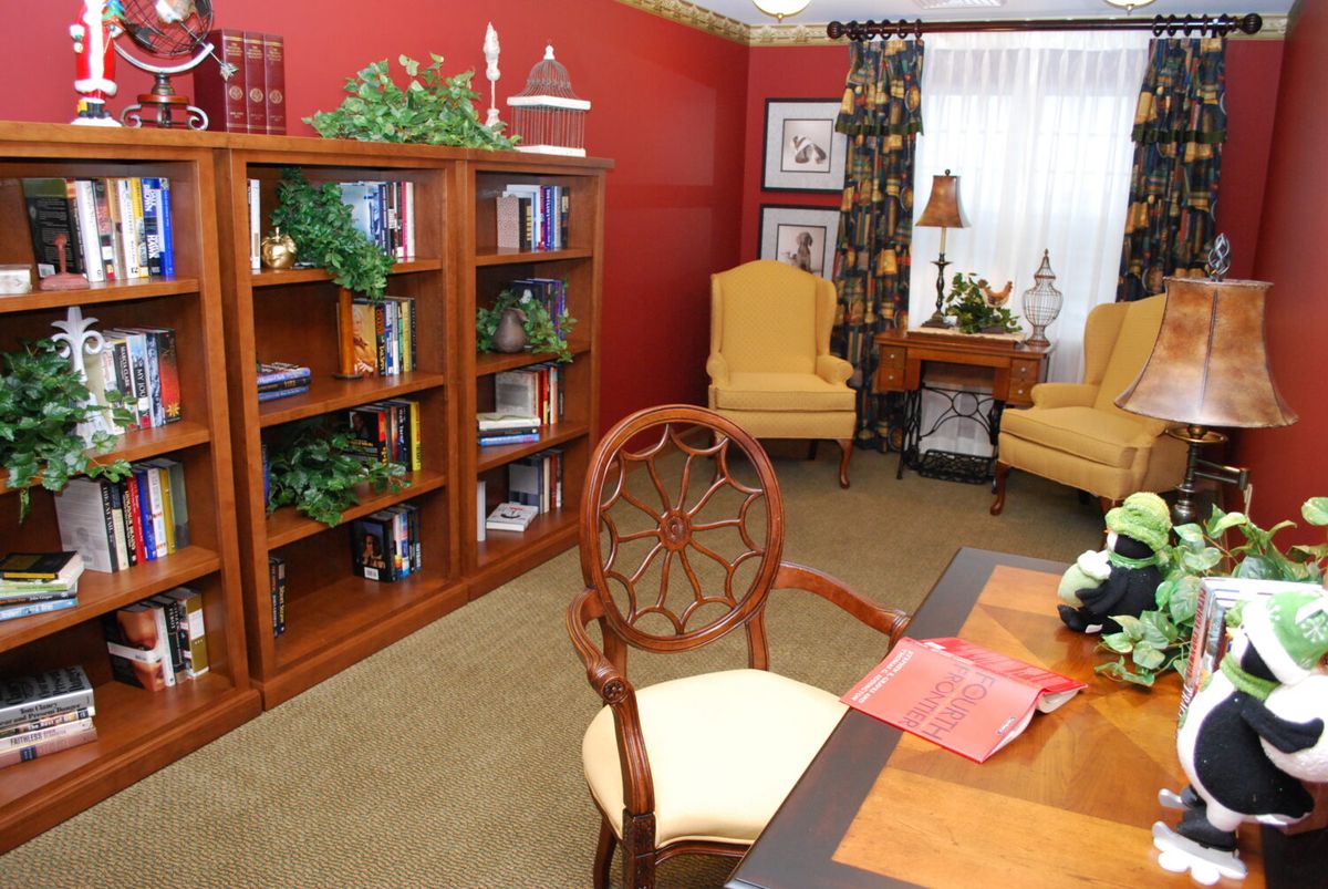 A cozy home library with bookshelves and comfortable reading chairs.