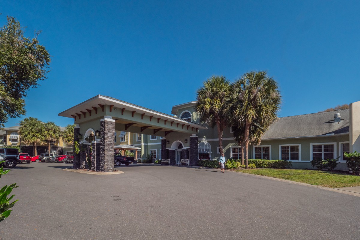 A building entrance with palm trees under a clear blue sky.