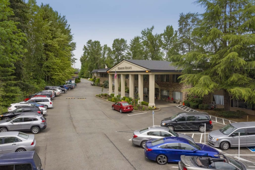 A building with columns surrounded by a parking lot and trees.