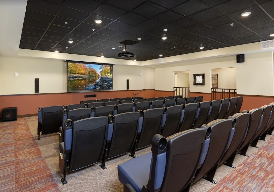 An empty auditorium with theater-style seating and a projection screen at the front.