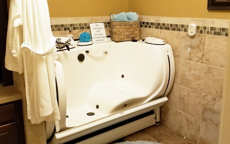 A luxurious indoor jacuzzi bathtub in a cozy bathroom setting with tiled walls and towels.