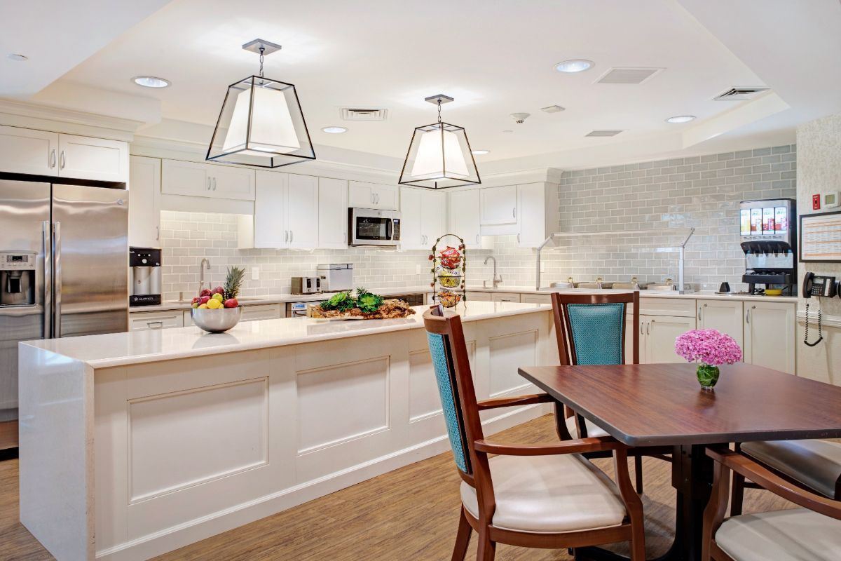 A modern kitchen with a spacious dining area featuring pendant lights and white cabinetry.